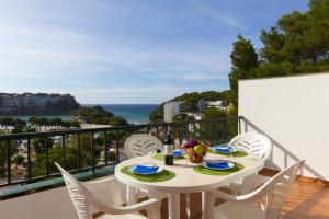 a table and chairs on a balcony with a view of the ocean at Apartamentos Encanto Del Mar in Cala Galdana
