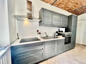 a kitchen with gray cabinets and a sink at Cá d'la trifola parcheggio gratuito in Alba