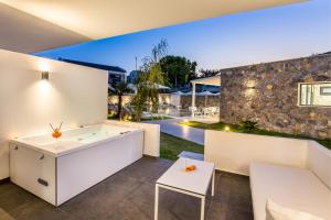 an outdoor living room with white furniture and a stone wall at Epicentrum Suites Fresh in Limenaria