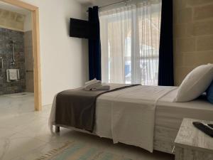 a bedroom with a large bed and a window at Fiftyfour West Boutique Living in Għarb