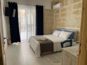 a bedroom with a bed and a large window at Fiftyfour West Boutique Living in Għarb