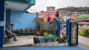 a man sitting on a bench next to a fence with plants at Finteo Skylands in Baguio