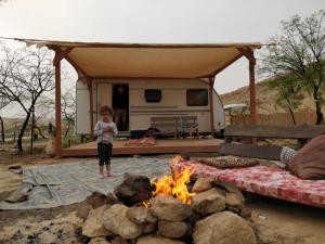 a little girl standing in front of a campfire at השקדיה - Shkedya in Mitzpe Ramon