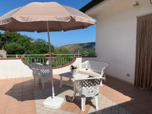 einen Tisch und Stühle mit Sonnenschirm auf einer Terrasse in der Unterkunft La Tenuta B&B in Buonvicino