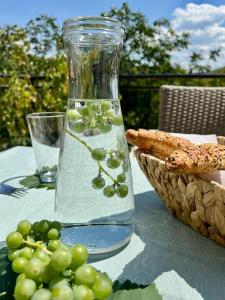 a glass vase filled with water next to a basket of grapes at Vikendica Oliver in Medovdolac