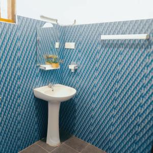 a blue tiled bathroom with a sink and a mirror at Jaana Guest in Sigiriya