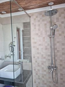 a bathroom with a glass shower with a sink and a tub at Vromos Guest Rooms in Chernomorets +30 photos
