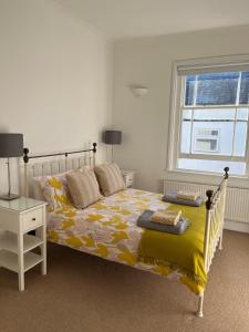 1 dormitorio con 1 cama con manta amarilla y ventana en Tree Tops Apartment in Tunbridge Wells, en Royal Tunbridge Wells
