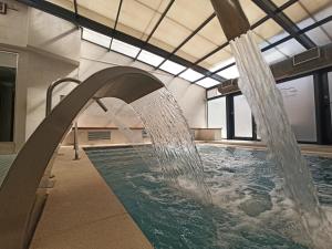 - une piscine avec une fontaine dans un bâtiment dans l'établissement ARVA Spa París, à León