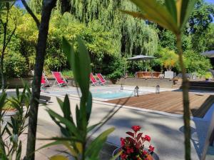 a swimming pool with chairs and a wooden deck at Lili Paradis in Saint-Savin