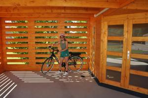 una mujer sosteniendo una bicicleta en un garaje de madera en Ferienhaus Altmann 2, en Sankt Magdalena
