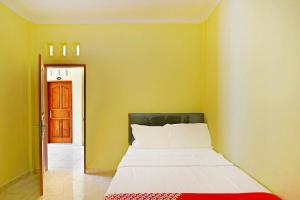 Bett in einem Zimmer mit gelber Wand in der Unterkunft OYO Life 90675 Ld Residence in Ungasan