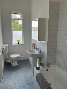 Baño blanco con lavabo y aseo en Tree Tops Apartment in Tunbridge Wells, en Royal Tunbridge Wells