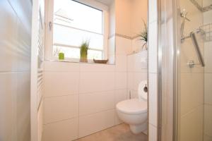 a white bathroom with a toilet and a window at Ferienwohnung Whg.3 im Haus Sarah in Büsum +1 photo