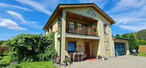 a small yellow house with a balcony on top at Spacious house with indoor pool & sauna. in Ādaži