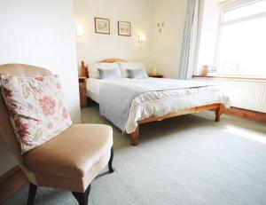 a bedroom with a bed and a chair and a window at Fernydale Farm Bed & Breakfast in Earl Sterndale