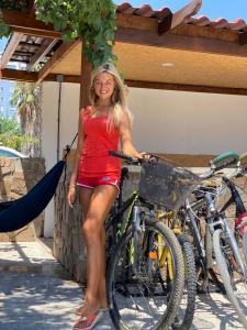 Eine Frau in einem roten Kleid steht neben einem Fahrrad in der Unterkunft CAMP&HOSTEL Antalya in Antalya