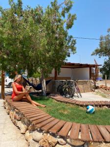a woman sitting on a wooden pathway reading a book at CAMP&HOSTEL Antalya in Antalya