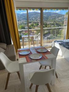 a dining room table with white chairs and a large window at Studio Cannes Marina Mandelieu in Mandelieu-la-Napoule