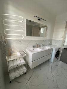 a white bathroom with a sink and a mirror at TWIN HOUSE in Gyál