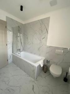 ein weißes Bad mit einer Badewanne und einem WC in der Unterkunft TWIN HOUSE in Gyál