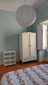 una camera con un armadietto bianco e un lampadario a braccio di Casa da Carqueja 1 a Coimbra