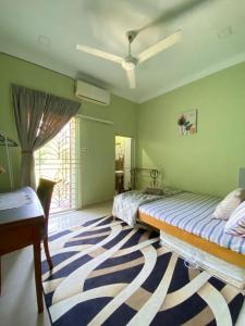 a bedroom with two beds and a desk and a rug at Darney's Homestay Kg Bangau Tanjung in Temerloh