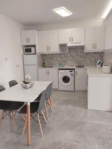 a kitchen with white cabinets and a table and chairs at Amazing Napa Apartment in Ayia Napa