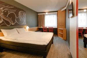 
a hotel room with a bed, desk, chair and a window at ibis Wien City in Vienna
