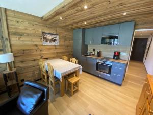 拉克吕萨Appartement 2 pièces ensoleillé avec Wi-Fi et parking, La Clusaz - FR-1-459-76的一间带桌子的厨房和一间带蓝色橱柜的厨房