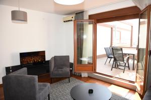 Relax lux في Vrnjačka Banja: غرفة معيشة بها موقد وطاولة وكراسي