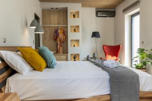 um quarto com uma grande cama branca e uma cadeira vermelha em El Mar Naxos em Naxos Chora