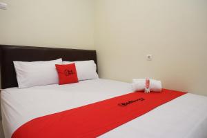 uma cama com almofadas vermelhas e brancas em RedDoorz Syariah at Kelud Sampangan Semarang em Jomblang