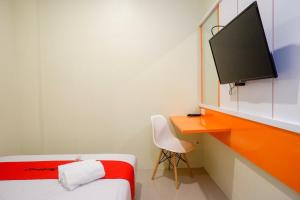 um quarto com uma cama e uma secretária com uma televisão em RedDoorz Syariah at Kelud Sampangan Semarang em Jomblang