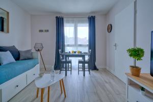 ein Wohnzimmer mit einem blauen Sofa und einem Tisch in der Unterkunft Logement Elia in Courcouronnes