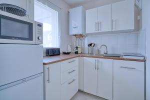 a white kitchen with white cabinets and a microwave at Logement Elia in Evry-Courcouronnes