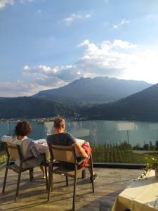 a man and woman sitting in chairs on a deck with a view at AGRITUR SEDICI - Bed and Breakfast in Tenna 