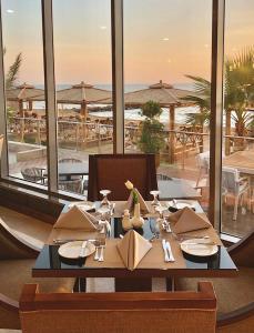 a table in a restaurant with a view of the ocean at Waves Hotel in Umm Lujj