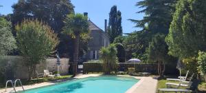 a swimming pool in front of a house with trees at Logis Des Bessons in Migron