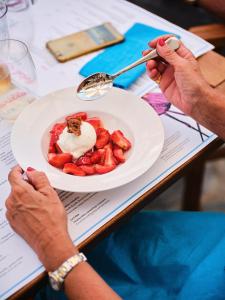 eine Person, die einen Teller Essen mit einer Schale Erdbeeren hält in der Unterkunft Hotel Carillon in Baveno