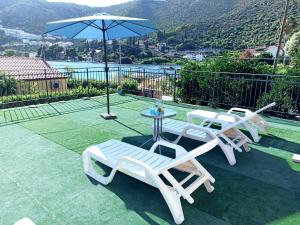 tres sillas blancas y una mesa y una sombrilla en Villa Tanya - modern 3 bedroom house seconds away from the sea, en Zaton
