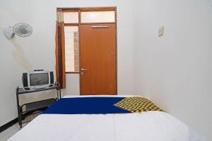 1 dormitorio con 1 cama, TV y puerta en SPOT ON 91394 Pondok Paskal Syariah en Bandung