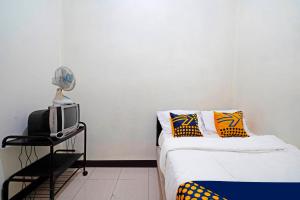 1 dormitorio con 1 cama, TV y ventilador en SPOT ON 91394 Pondok Paskal Syariah en Bandung