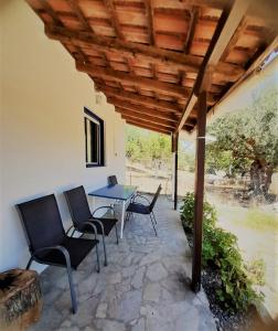 a patio with a table and chairs under a wooden roof at Stafida Guesthouse - Myrtò in Finikounta