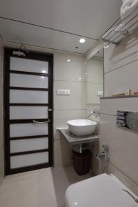 a bathroom with a toilet and a sink and a door at HOTEL THE LOTUS PARK in Ahmedabad