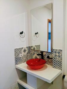 - une salle de bains avec un bol rouge sur un comptoir avec un miroir dans l'établissement OFF HOSTEL, à Villa de Leyva
