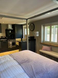a bedroom with a large bed and a kitchen at Honeysuckle Cottage - Hillside Holiday Cottages, Cotswolds in Warmington