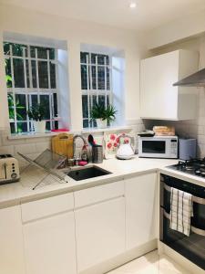 倫敦的住宿－2 Bedroom Apartment close to Camden Town，白色的厨房配有白色橱柜和水槽