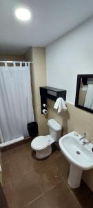 a bathroom with a white toilet and a sink at Hotel-Restaurante Ancora in Puerto López