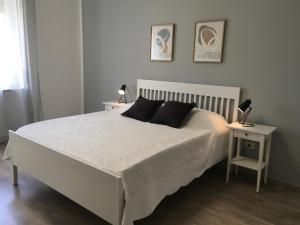 um quarto com uma cama branca e 2 candeeiros numa mesa em Casa di Babi em Verona